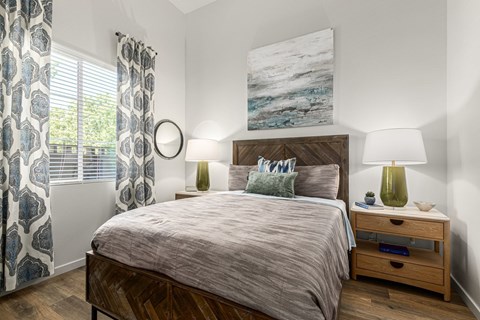 A bedroom with a large bed, a nightstand with a lamp, and a painting on the wall.