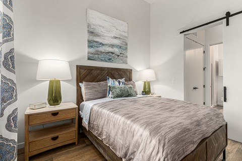 A bedroom with a bed, nightstand, and a painting on the wall.