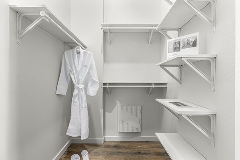 A white bathroom with a robe hanging on the rack.