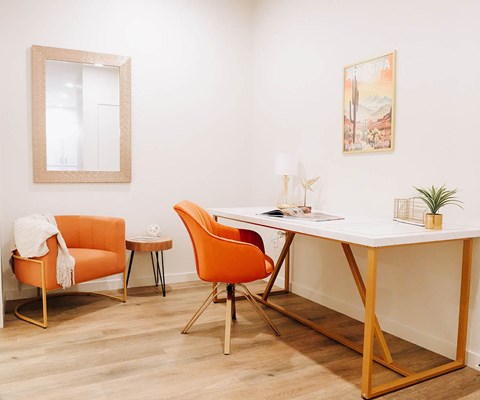A room with a desk, chair, and a mirror.
