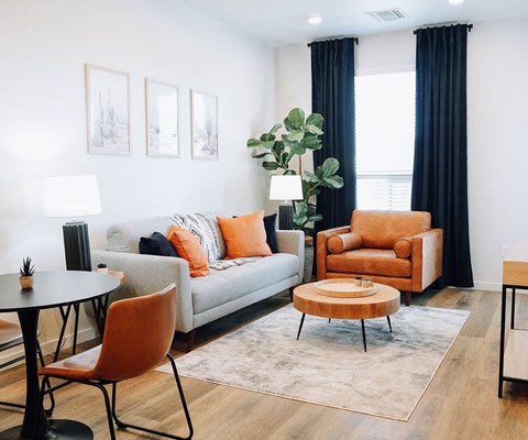 A living room with a grey couch, orange chairs, and a coffee table.