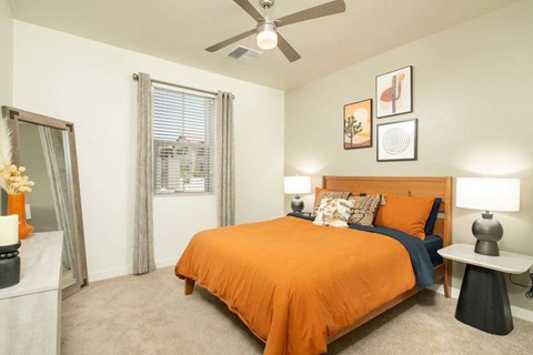 A bedroom with a bed, a ceiling fan, and a window with curtains.