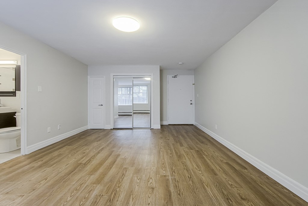 an empty living room with white walls and wood flooring at 107 Redpath, Toronto Canada