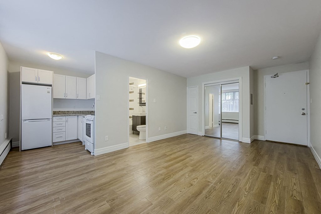 a renovated living room with a kitchen with white appliances at 107 Redpath, Canada