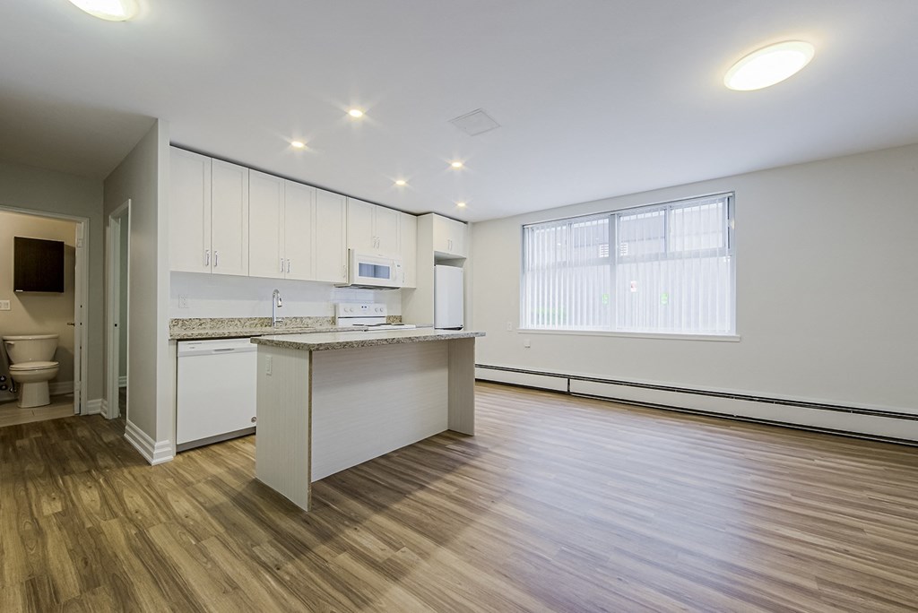 an empty living room and kitchen with white cabinets and a counter top at 107 Redpath, Toronto