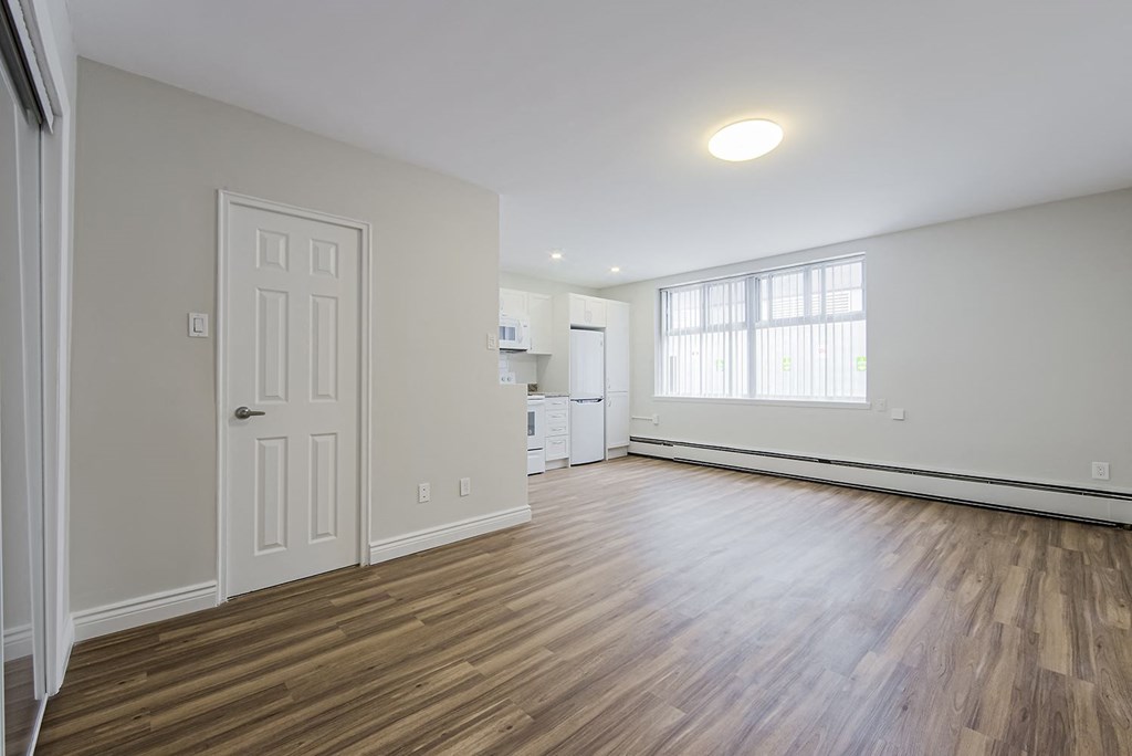an empty living room and kitchen with wood floors and a white door at 107 Redpath, Toronto, CA
