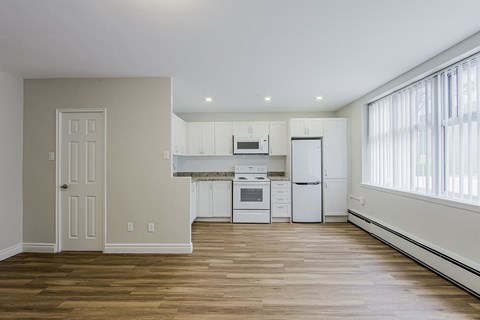 A kitchen with white appliances and wooden floors.