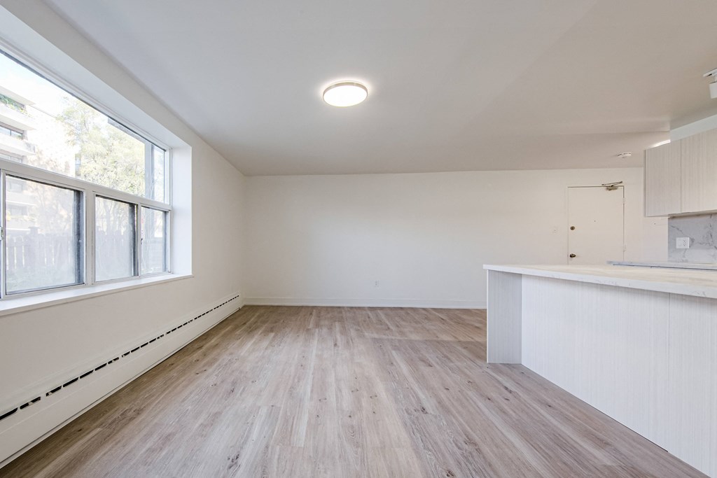an empty living room with a large window and a kitchen at 111 Cosburn, East York, ON M4J 2L1
