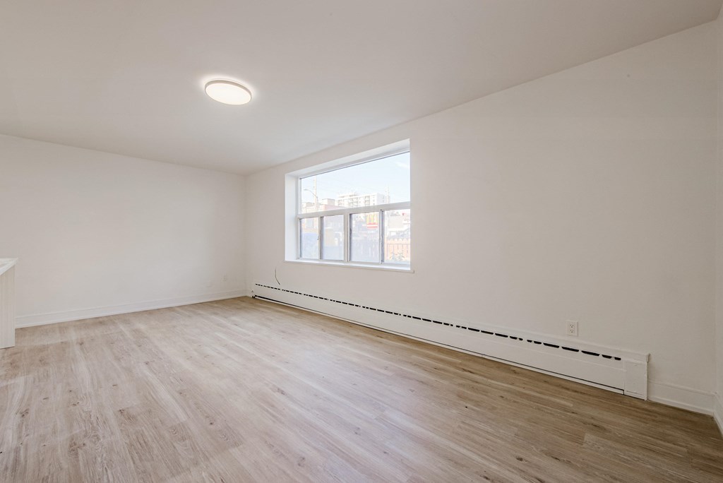 the living room of an apartment with wood flooring and a window at 111 Cosburn, East York, ON