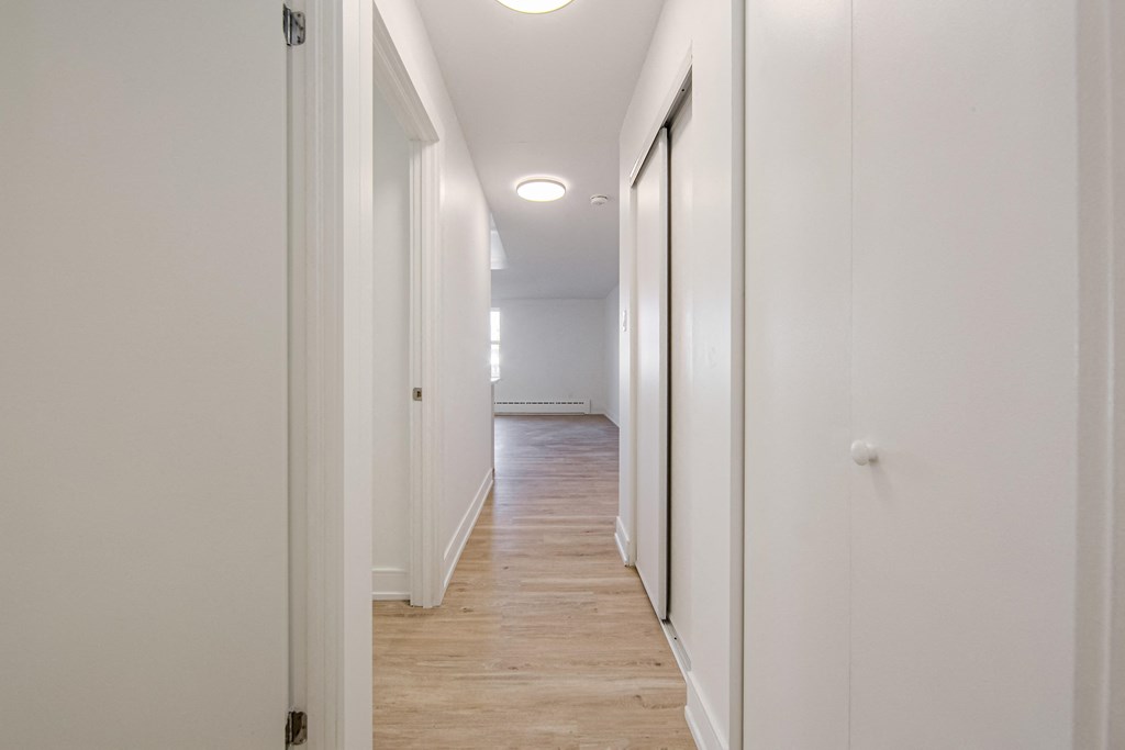 a hallway with white walls and white wood floors and a white ceiling with a light at 111 Cosburn, Ontario, M4J 2L1