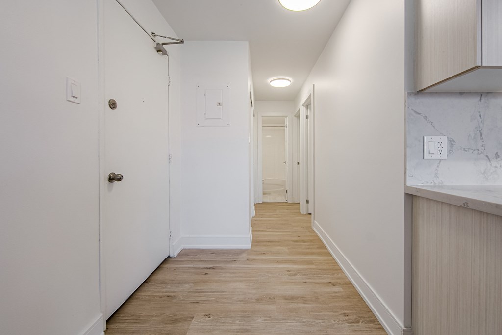a long white hallway with white walls and wood floors at 111 Cosburn, East York, ON