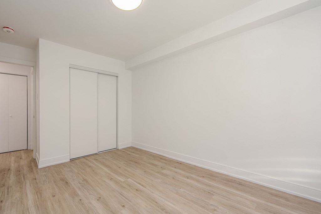an empty room with white walls and wooden floors and a door at 111 Cosburn, Ontario