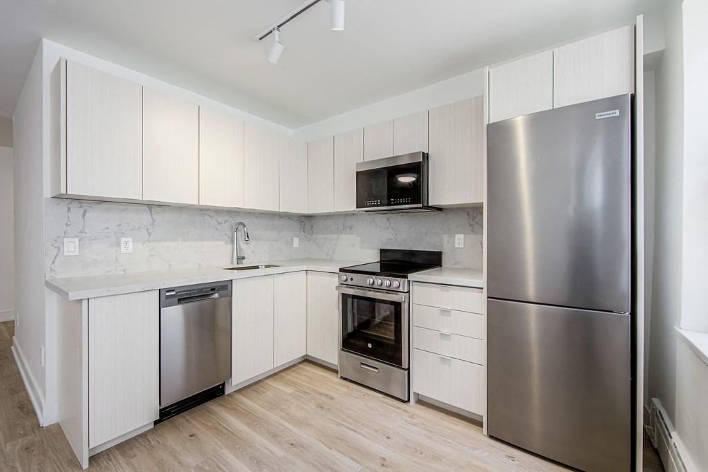 a kitchen with white cabinets and stainless steel appliances and a refrigerator at 111 Cosburn, East York, ON