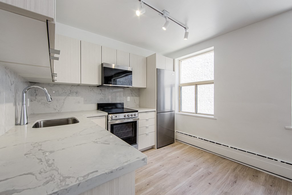 a kitchen with marble counter tops and white cabinets at 111 Cosburn, East York