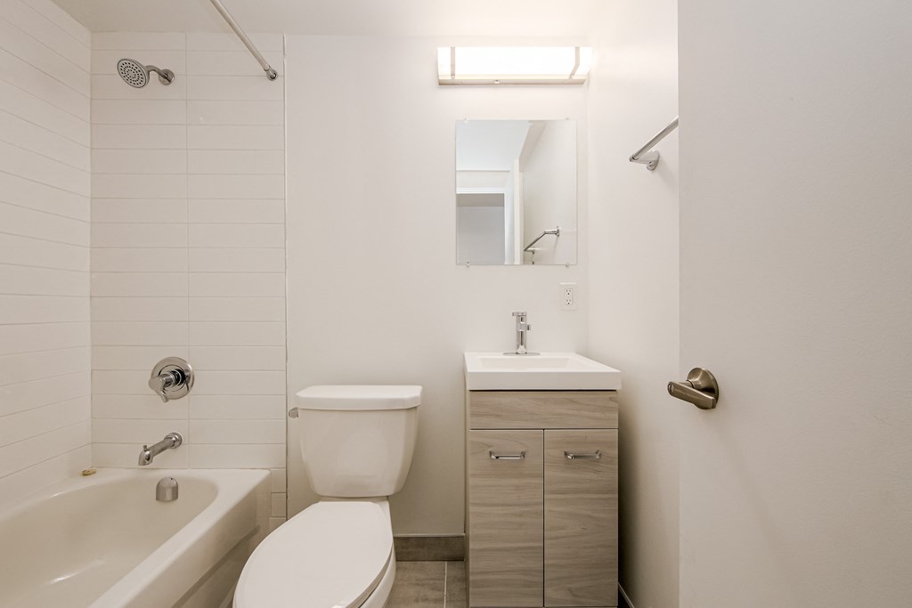 a bathroom with a toilet sink and tub and a mirror at 111 Cosburn, East York, ON M4J 2L1