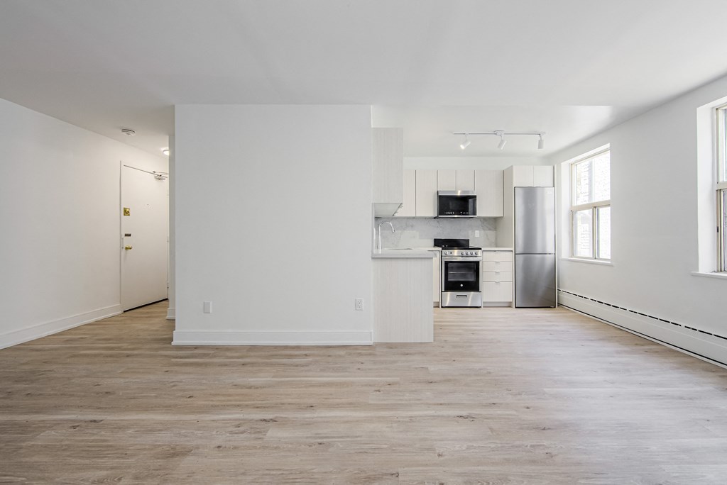 an empty living room with white walls and a kitchen at 111 Cosburn, Ontario