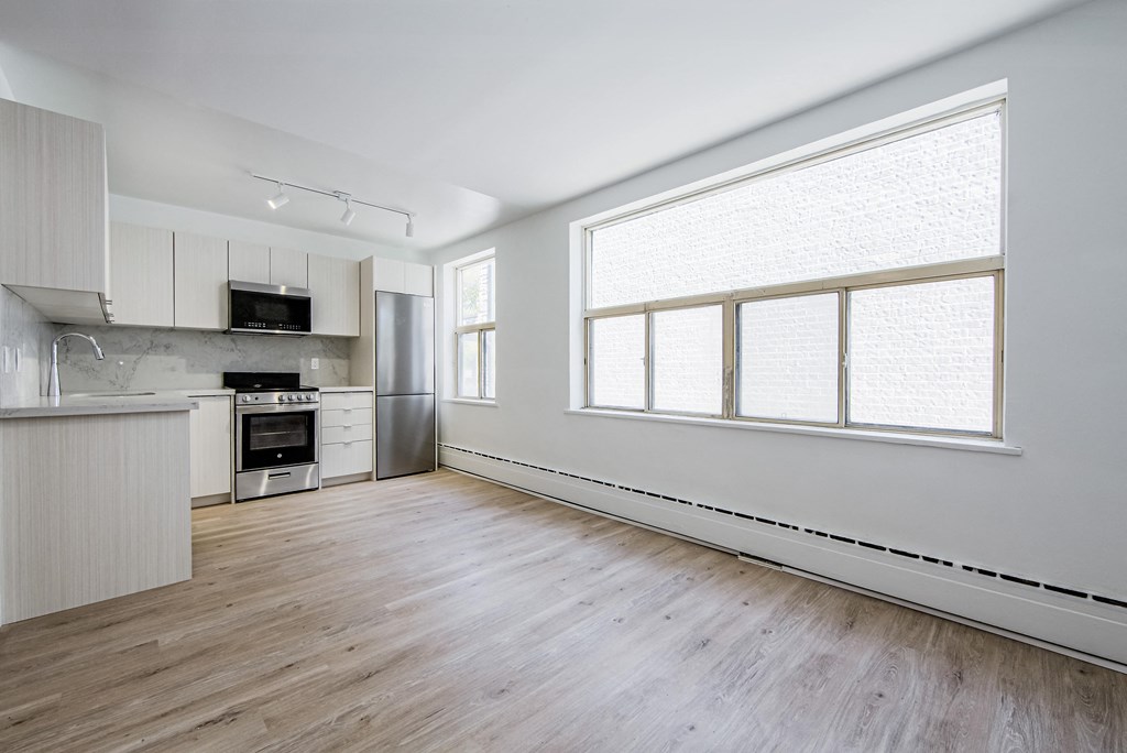 an empty kitchen with white cabinets and a large window at 111 Cosburn, East York, M4J 2L1
