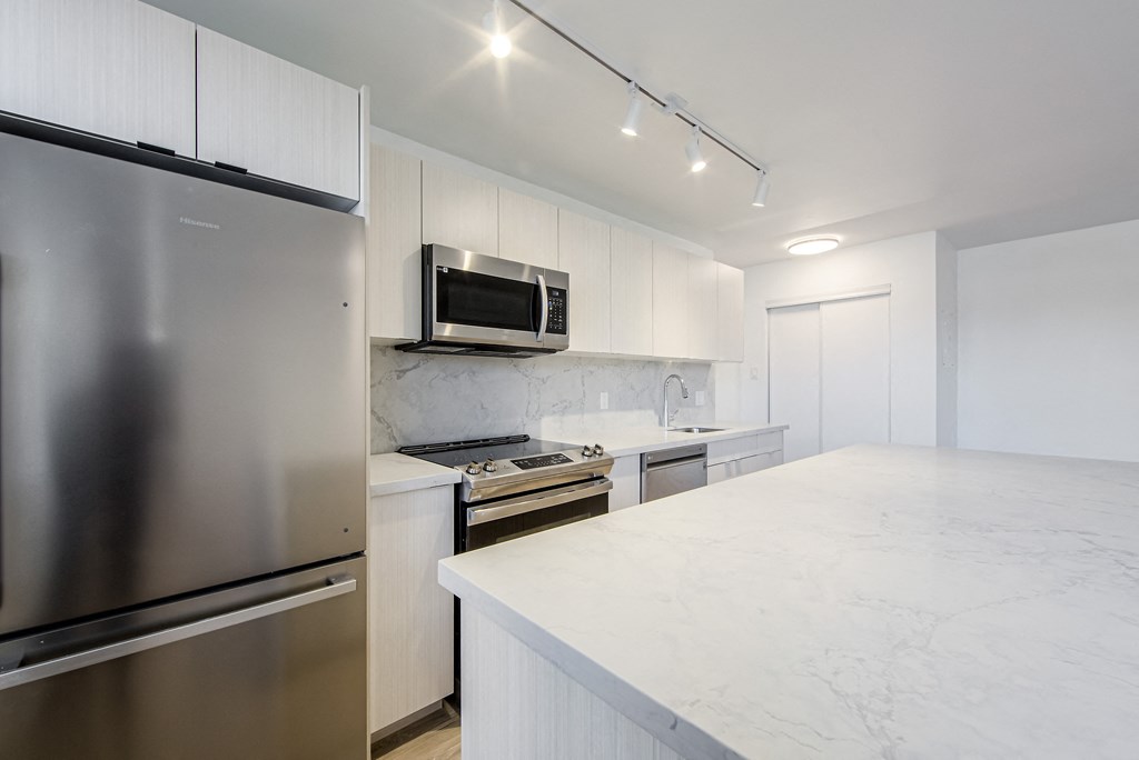 a kitchen with white marble counter tops and stainless steel appliances at 111 Cosburn, East York, ON
