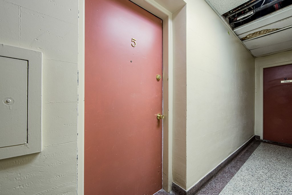 a red door in a hallway of a building with a door number on it at 111 Cosburn, Ontario