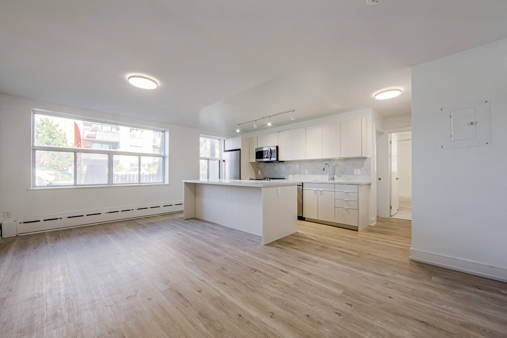 an empty living room with a kitchen and a large window at 111 Cosburn, East York Ontario