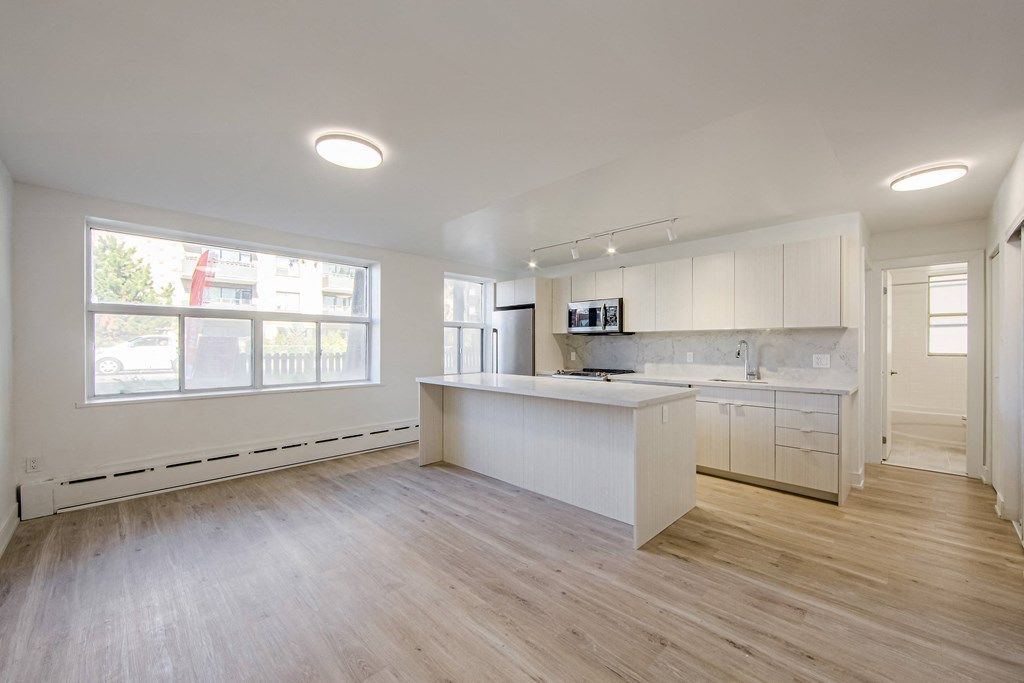 an empty kitchen with white cabinets and a large window at 111 Cosburn, East York Ontario