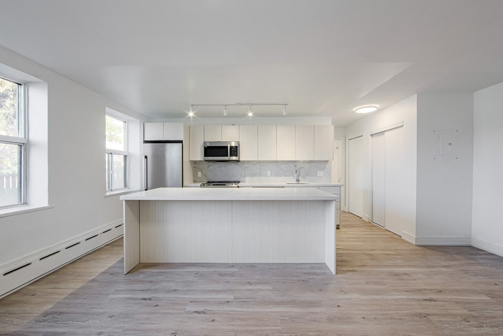 an empty kitchen with white cabinets and a white counter top at 111 Cosburn, Ontario, M4J 2L1