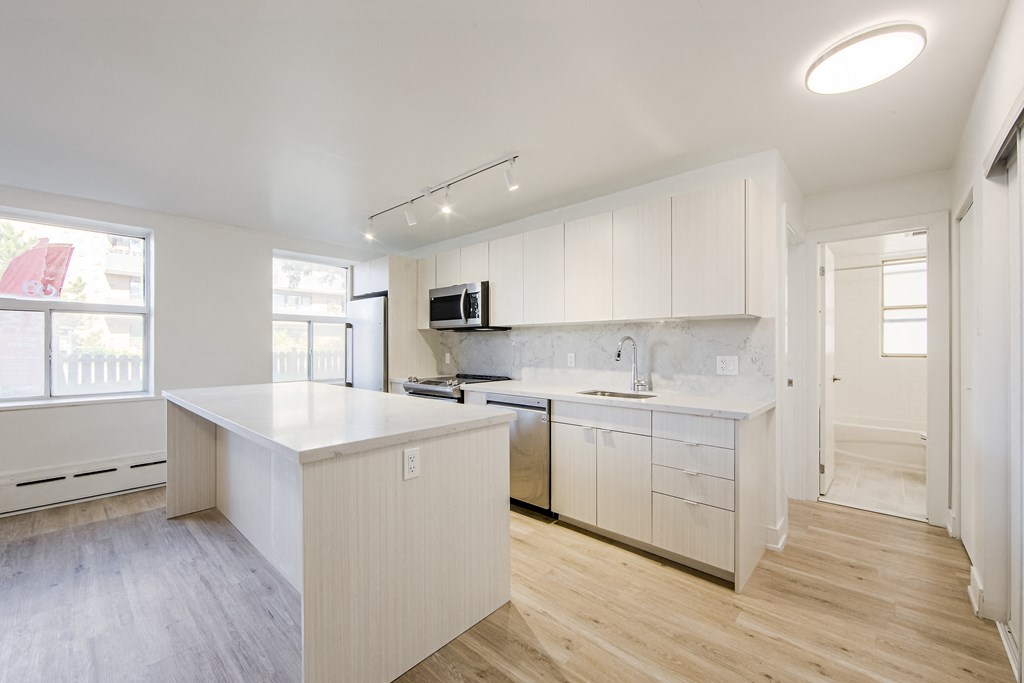 an empty kitchen with white cabinets and a large counter top at 111 Cosburn, East York, M4J 2L1