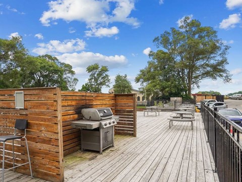 A wooden deck with a grill and picnic table.