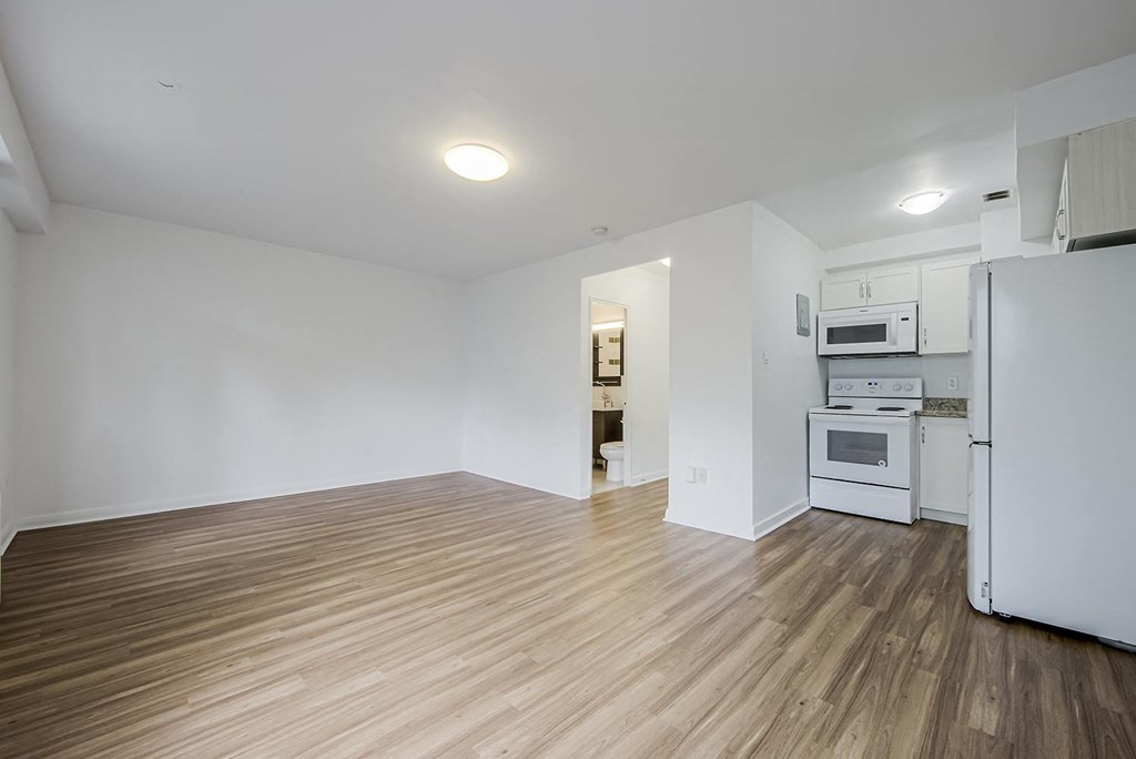 an empty living room and kitchen with white walls and wood floors at 161 St. George, Toronto, M5R 2M3