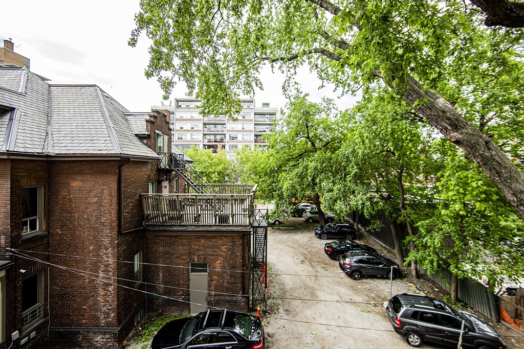 a city street with cars parked in front of a brick building at 161 St. George, Toronto Canada