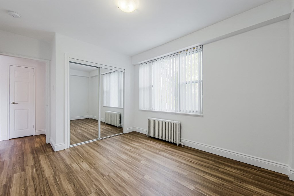 an empty living room with a mirrored closet and a window at 161 St. George, Toronto Canada