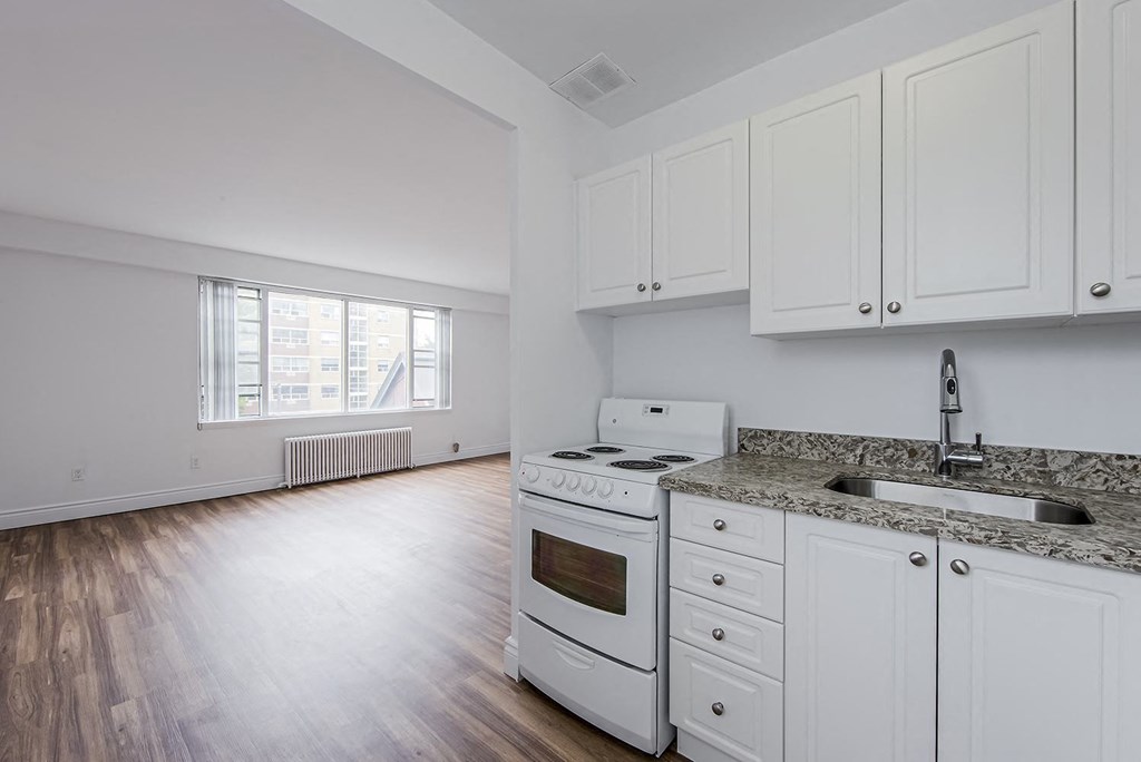 an empty kitchen with white appliances and white cabinets at 161 St. George, Toronto