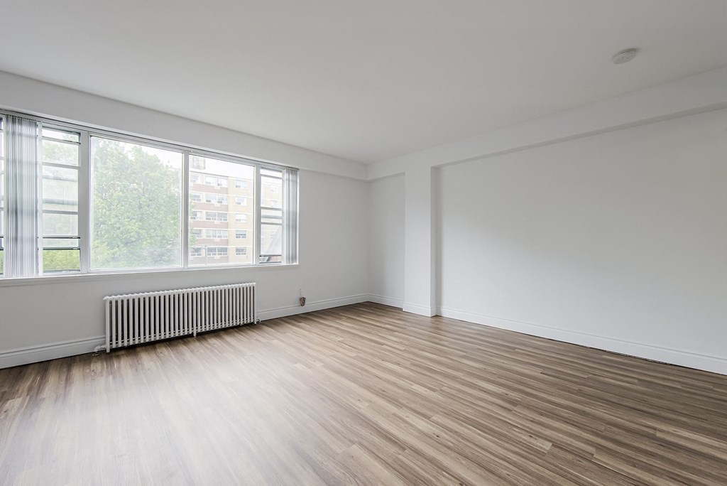 an empty living room with wood floors and a large window at 161 St. George, Toronto, M5R 2M3