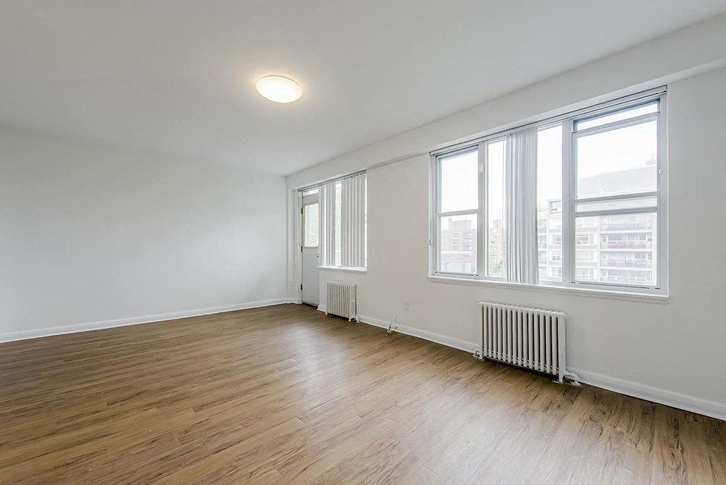 an empty living room with wood floors and large windows at 161 St. George, Toronto