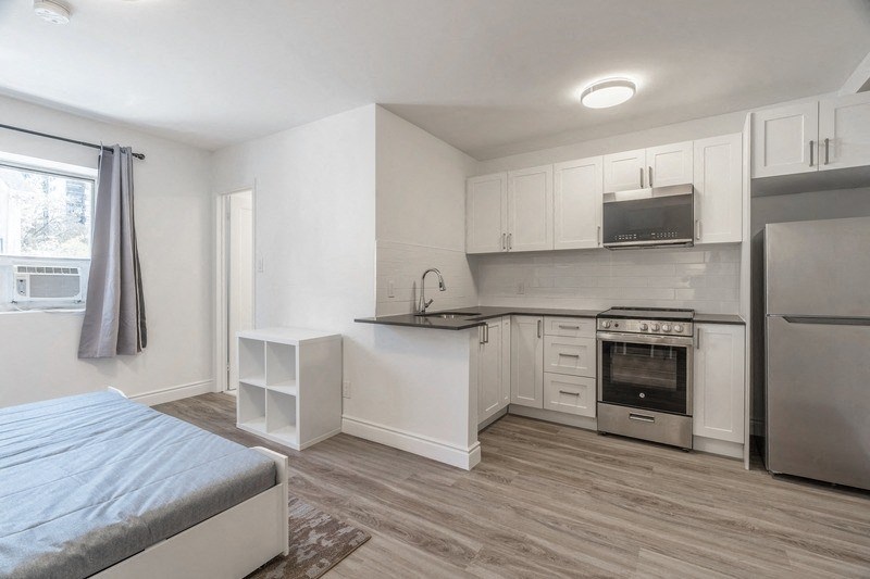a bedroom with a bed and a kitchen with a refrigerator at 608 Church Apartments, Toronto, Ontario