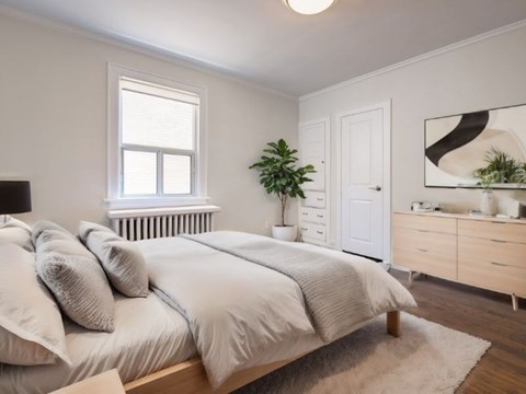 A bedroom with a large bed, a window, a dresser, and a mirror.