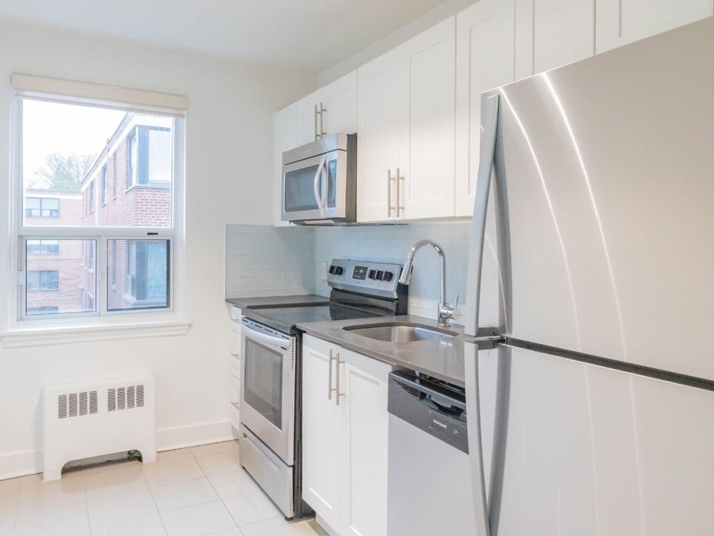 A white kitchen with a black fridge and stove.