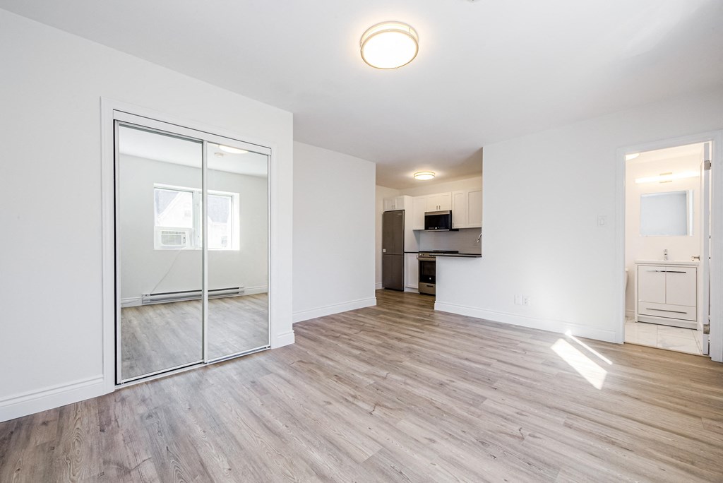 an empty living room with a mirror and a kitchen at 608 Church Apartments, Toronto