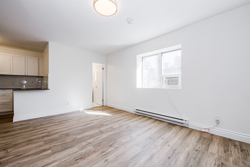 an empty living room with white walls and wood floors at 608 Church Apartments, Toronto, ON
