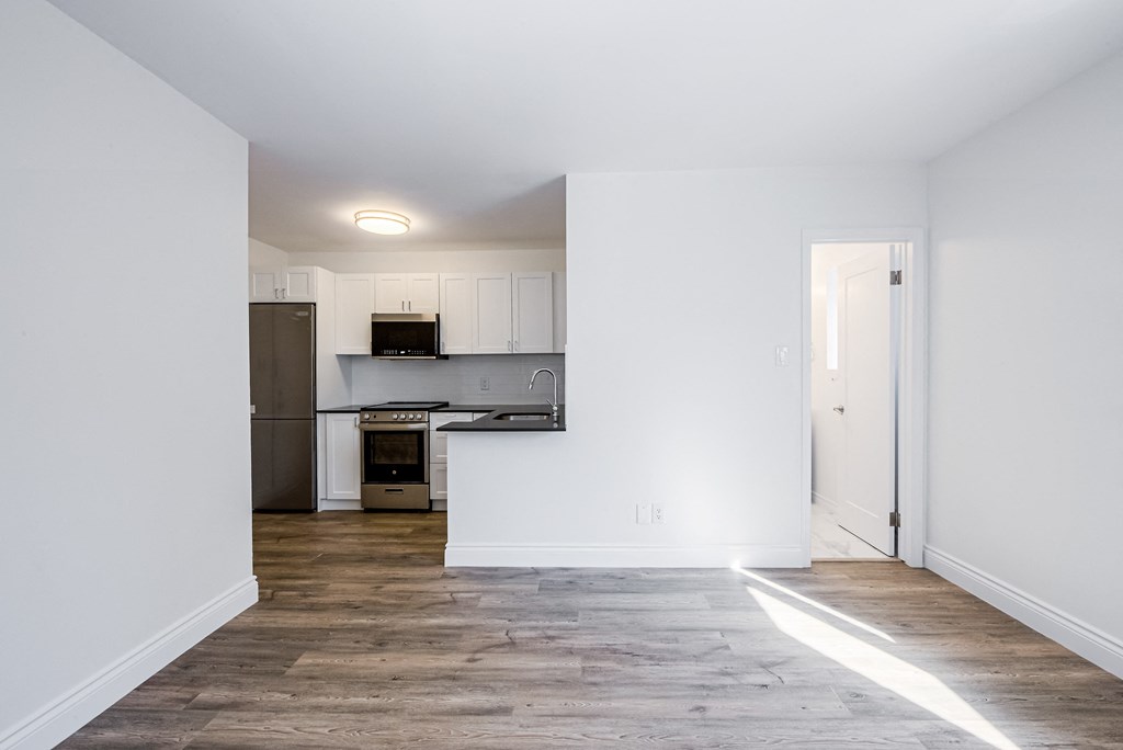 a living room and kitchen with white walls and wood flooring at 608 Church Apartments, Toronto, ON