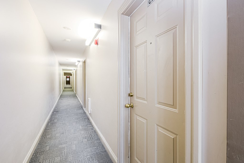 a long white hallway with white doors and a carpeted floor at 608 Church Apartments, Toronto, M4Y 2E7