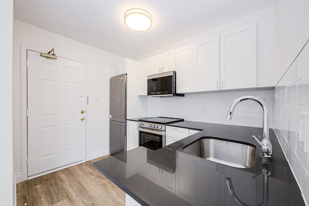 a renovated kitchen with stainless steel counter tops and white cabinets at 608 Church Apartments, Ontario