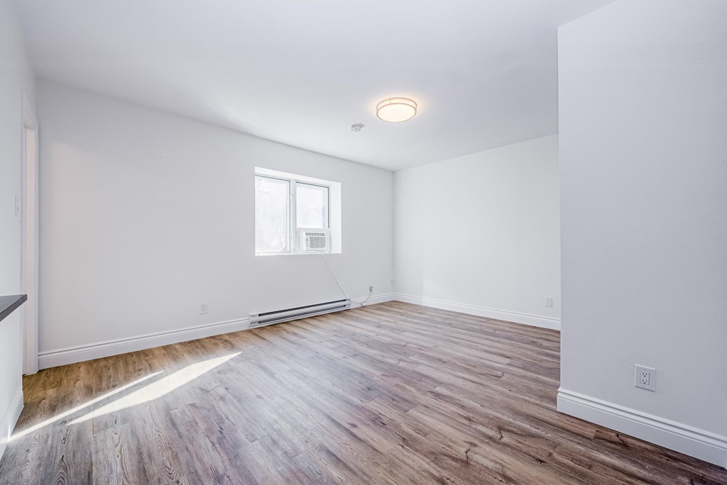 an empty living room with white walls and wood flooring at 608 Church Apartments, Toronto, M4Y 2E7