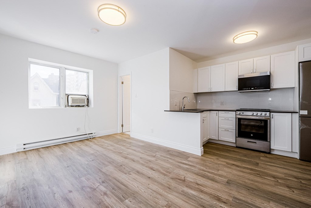 an empty kitchen with white cabinets and a wood floor at 608 Church Apartments, Toronto, Ontario
