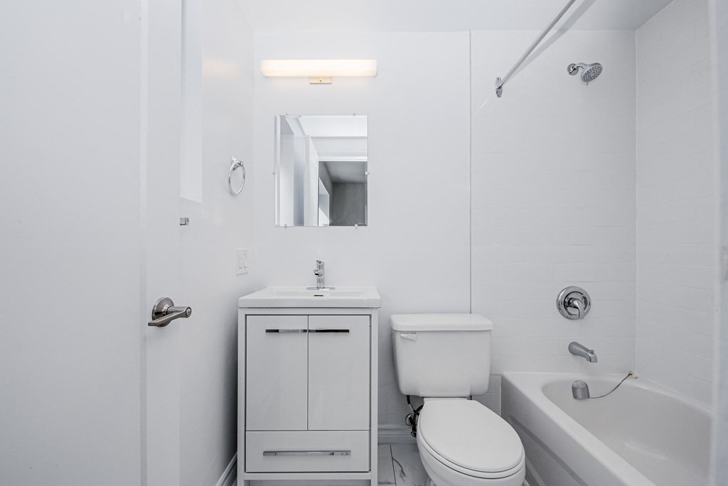 A white bathroom with a toilet, sink, and bathtub at 608 Church Apartments, Ontario, M4Y 2E7