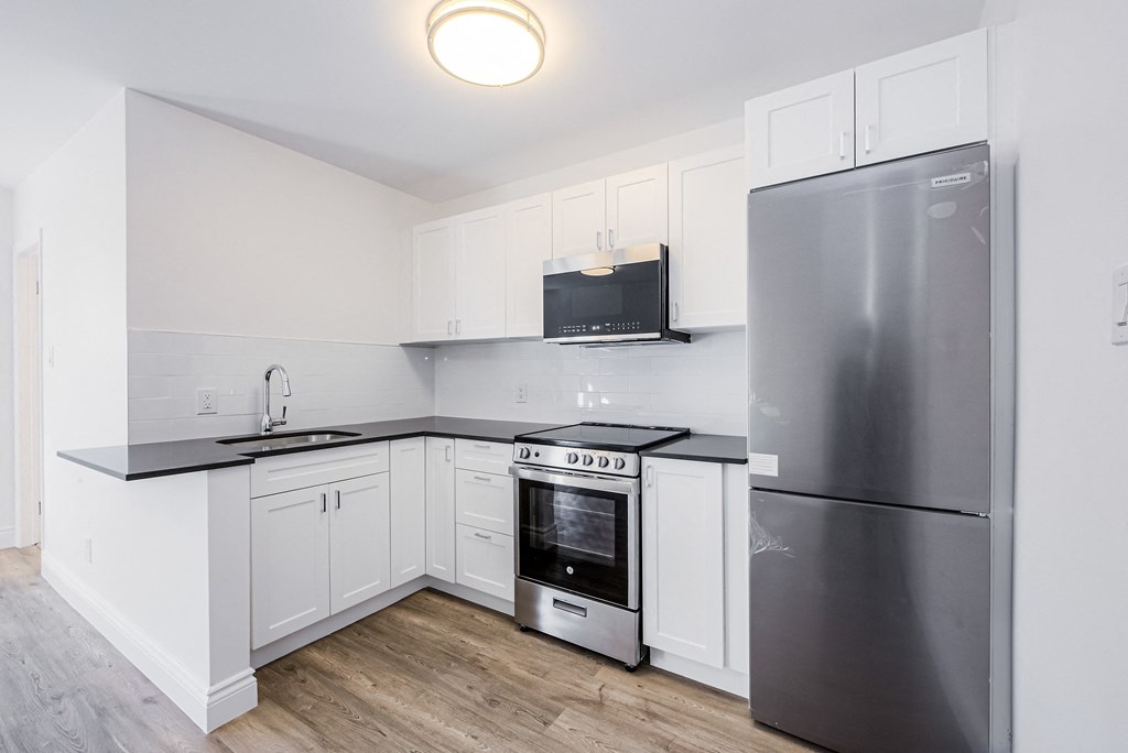 A kitchen with a refrigerator, oven, and microwave at 608 Church Apartments, Toronto