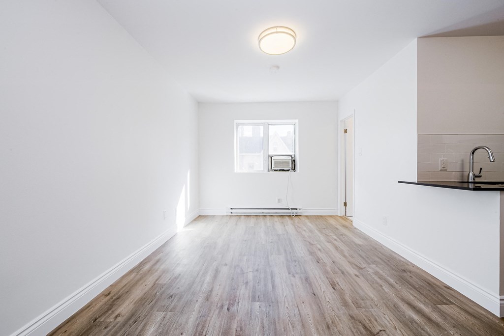 an empty living room with white walls and wood floors at 608 Church Apartments, Ontario
