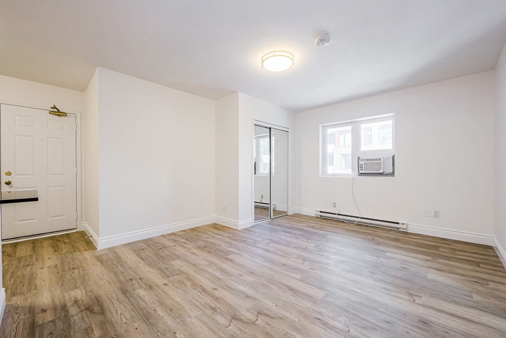 an empty living room with white walls and wood flooring at 608 Church Apartments, Toronto, ON