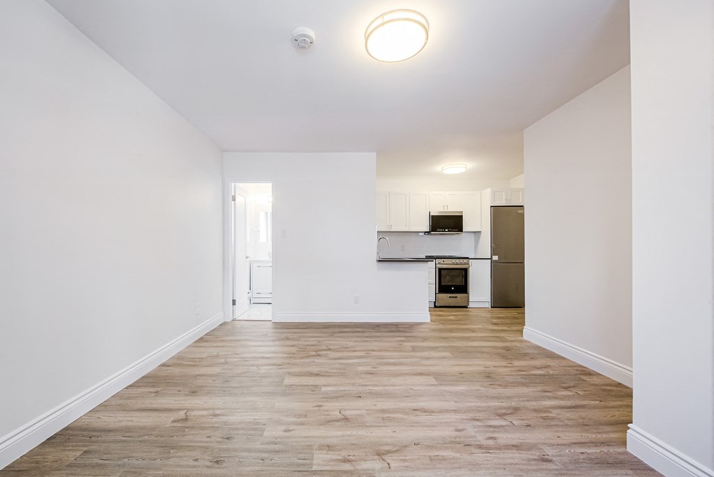 an empty living room with white walls and a kitchen at 608 Church Apartments, Toronto, ON