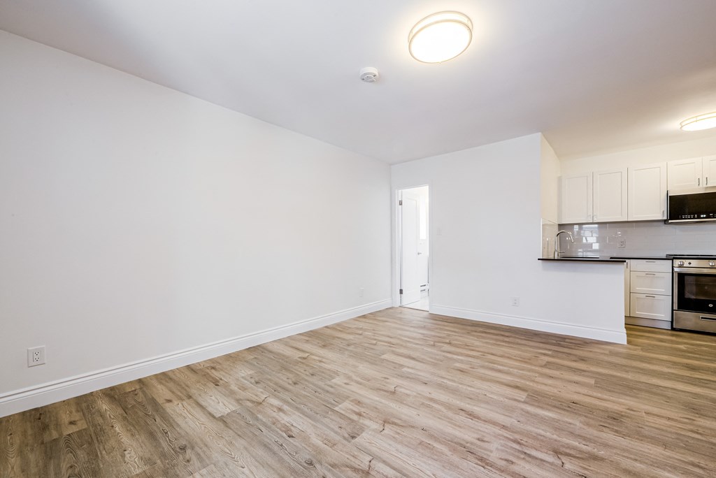 the living room and kitchen of an apartment with wood floors and white walls at 608 Church Apartments, Toronto